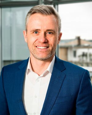 Porträtfoto eines Geschäftsführers in Business-Kleidung in einem hellen Büro